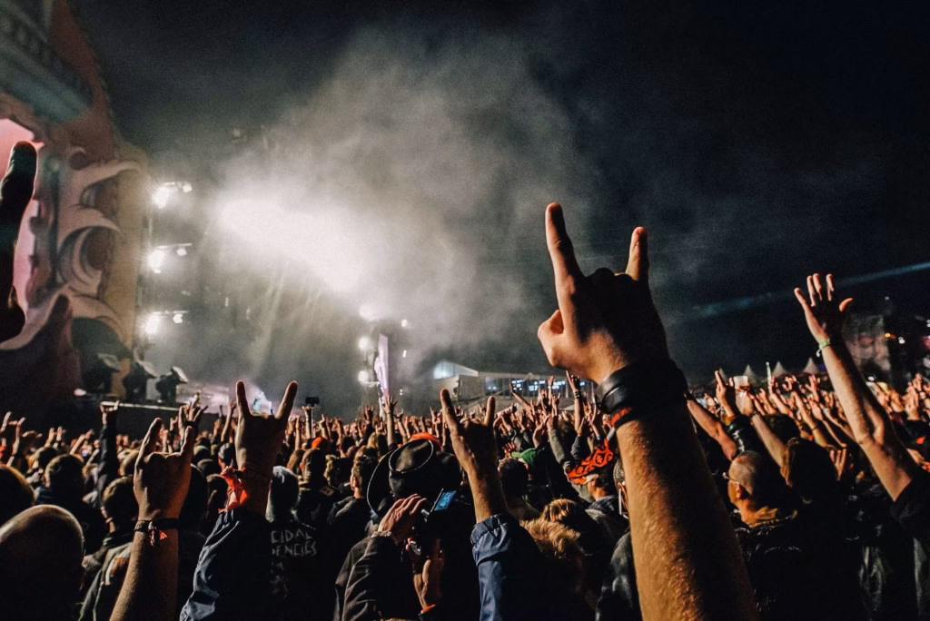 Photo d'une foule de concert rock. Plusieurs mains levées faisant le symbole des "devil horns"